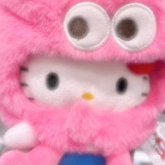 a hello kitty stuffed animal with big eyes and a pink fur coat over it's head