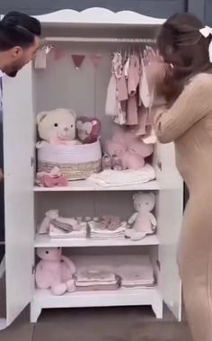 a man and woman standing in front of a white shelf with stuffed animals on it