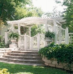 a white gazebo sitting in the middle of a lush green yard with steps leading up to it