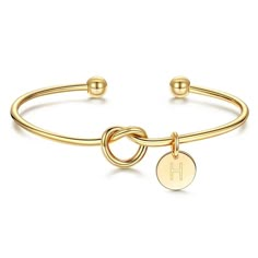 a gold bracelet with two circles and a initial charm on the clasp, in front of a white background