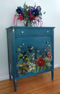 a blue cabinet with flowers and butterflies painted on it