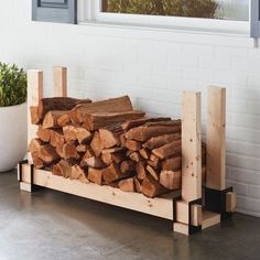 a pile of wood sitting on top of a wooden stand next to a potted plant