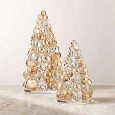 two glass christmas trees sitting on top of a table