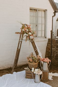 an old ladder with flowers on it next to a window and some other things in front of it