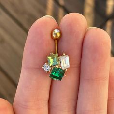 a person is holding an emerald and diamond navel ring