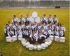 the band is posing for a photo in front of their drums and drum set on the field