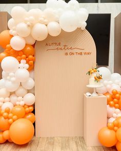 an orange and white balloon arch is set up on the floor for a wedding ceremony