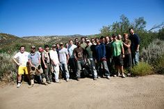 a group of men standing next to each other on a dirt road in the desert