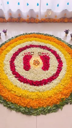 a circular flower arrangement on the floor in front of a white table cloth with red, yellow and orange flowers