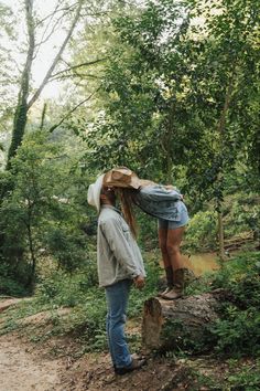 a woman standing on top of a tree stump in the middle of a wooded area