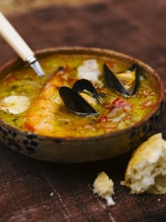 a bowl of soup with mussels on the side