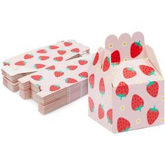 a pink box with strawberries on it next to a stack of paper napkins