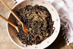 a bowl filled with seaweed and two wooden spoons