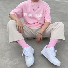 a woman sitting on the ground wearing pink and white tennis shoes with her legs crossed