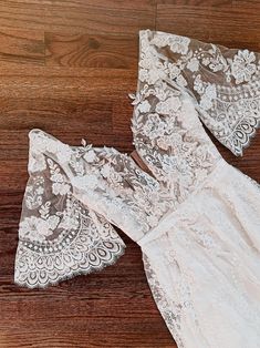 two pieces of white lace sitting on top of a wooden floor