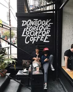 two people sitting on a bench in front of a coffee shop