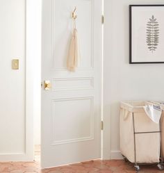 a baby crib next to a white door with a plant hanging on the wall