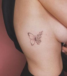 a woman's breast with a butterfly tattoo on her left side ribcage