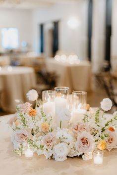 a centerpiece with candles and flowers on a table