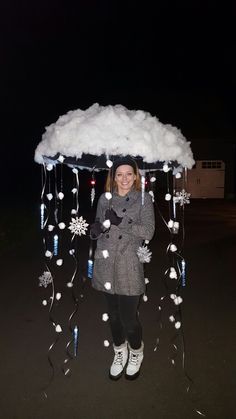 a woman is standing under an umbrella with snowflakes hanging from it and smiling