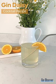 a pitcher of water with orange slices and daisies on the side next to it