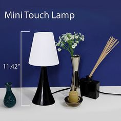 the mini touch lamp is next to two vases with flowers and reeds in them