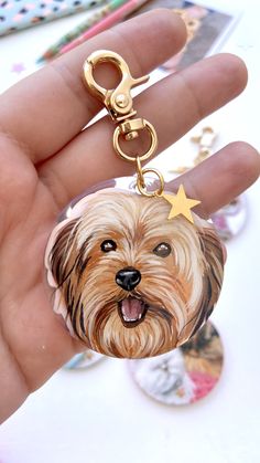 a hand holding a keychain with a dog on it's face and stars