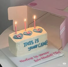 a birthday cake with three candles on it in front of a box that says, this is your came