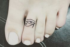 a woman's foot with an egyptian eye tattoo on her left toe and the bottom part of her finger