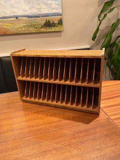 a wooden book shelf sitting on top of a table next to a potted plant