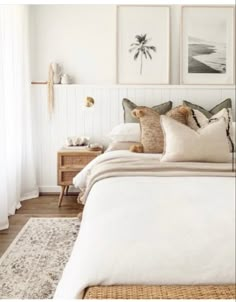 a bed with white sheets and pillows in a bedroom next to two pictures on the wall