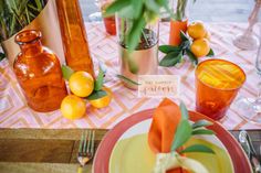 the table is set with oranges, lemons and glass vases on it