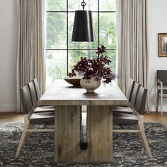 a dining room table with chairs and a vase on it in front of a window