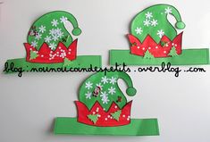 three green and red paper hats with snowflakes on them are hanging from the wall