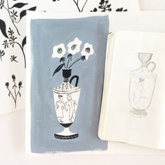 some drawings are sitting next to each other on a table with flowers in a vase