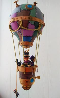 a colorful hot air balloon with people on it's sides and ropes hanging from the ceiling