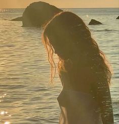 a woman standing in the water with her back to the camera