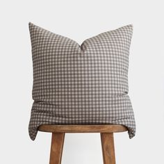 a grey and white checkered pillow sitting on top of a wooden stool