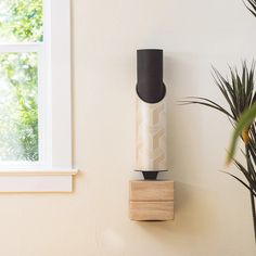 a white vase sitting on top of a wooden block next to a window sill