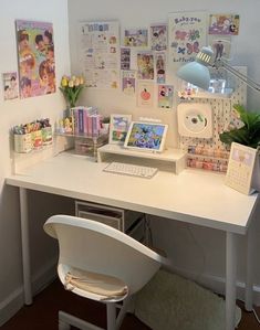 a white desk topped with a laptop computer next to a plant and pictures on the wall