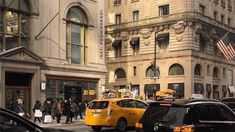 cars are parked on the street in front of tall buildings with flags flying from them