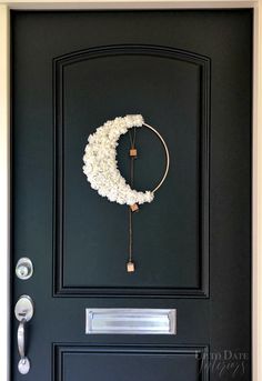 a black door with a white wreath on it and a metal handle to the side