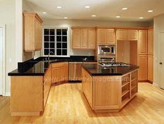 an empty kitchen with wooden cabinets and black counter tops in the middle of the room