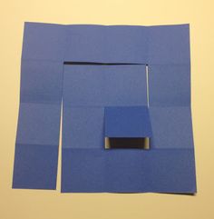 a blue piece of paper with a square cut out on the bottom and an object in the middle