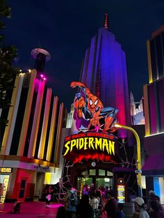 the entrance to an amusement park at night with people walking around and onlookers