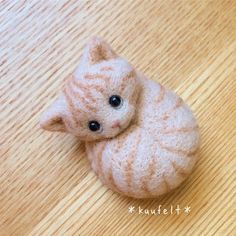 a small stuffed cat sitting on top of a wooden floor