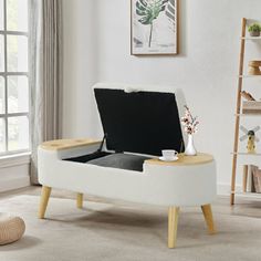 a living room with a white couch and coffee table on it's legs, in front of a window