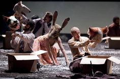 several people dressed as rabbits are sitting in open boxes on the ground, with one person reaching for an object