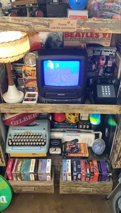 an old television sitting on top of a wooden shelf filled with books and other items