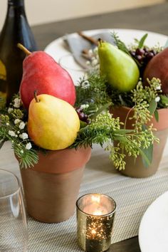 a table topped with vases filled with fruit and greenery